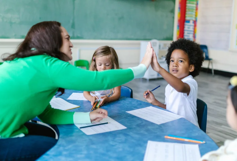 niño chocando la mano con su maestra